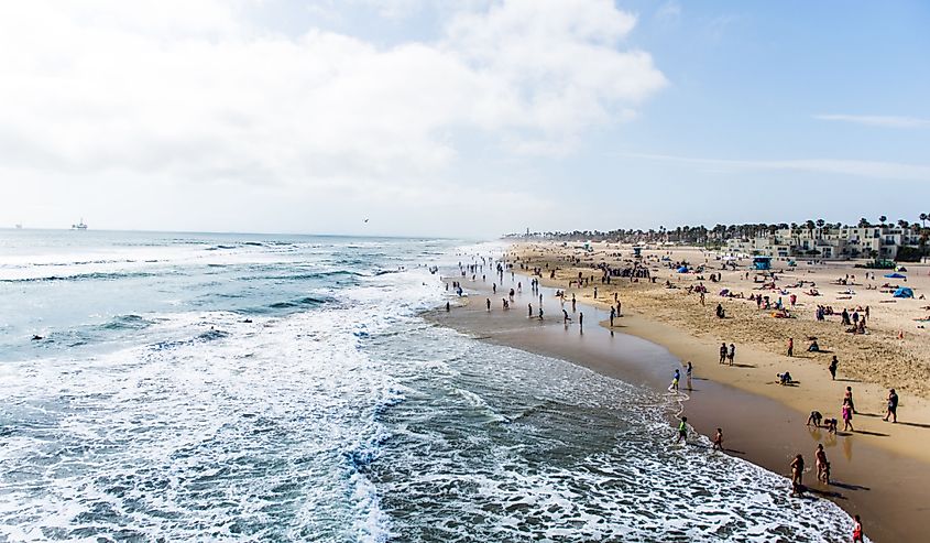 Crowds of tourists and sun bathers having fun and swimming at Huntington Beach, California