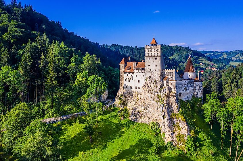 A small, ancient castle stands amongst the lush green mountains of Transylvania. 