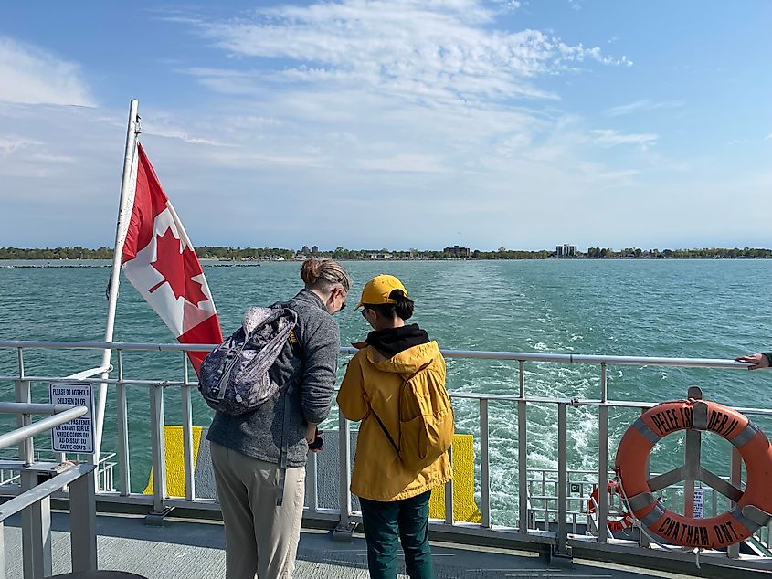 Two women stand beside a Canadian flag on the back of a lake ferry.