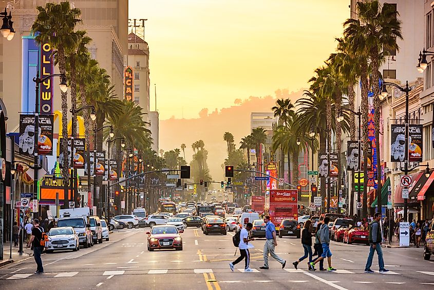 Pedestrians cross traffic on Hollywood Boulevard at dusk