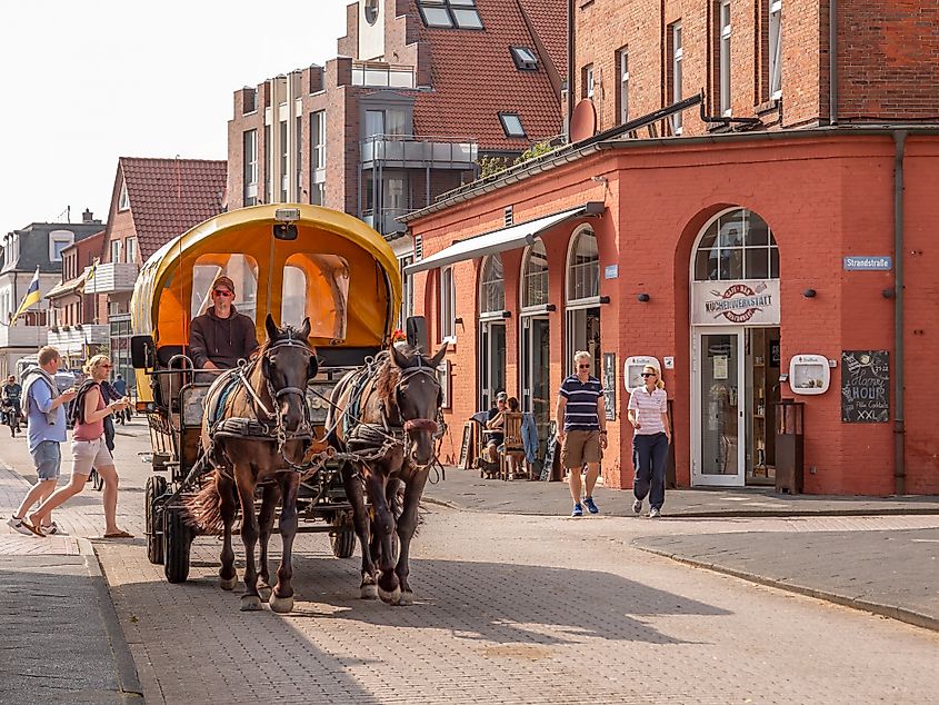 Horse-drawn carriage and people walking in town of East Frisian island Juist, Lower Saxony, Germany.