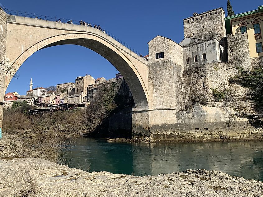 A low angle, riverside shot of the single-arch Old Bridge (Stari Most) in Mostar. 