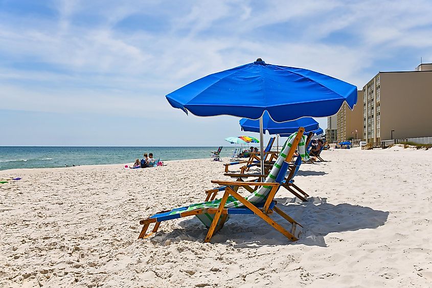 Beachgoers with beach chairs and umbrellas at Gulf Shores Beach, Gulf of Mexico.