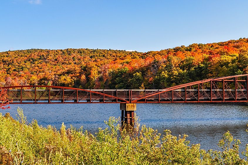 A bridge crosses a small lake near in front of the autumn colors near Rutland, Vermont.