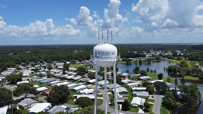 Aerial view of a water tower labeled “Leesburg The Lakefront City” rising above a residential neighborhood with lakes and trees in Leesburg, Florida.