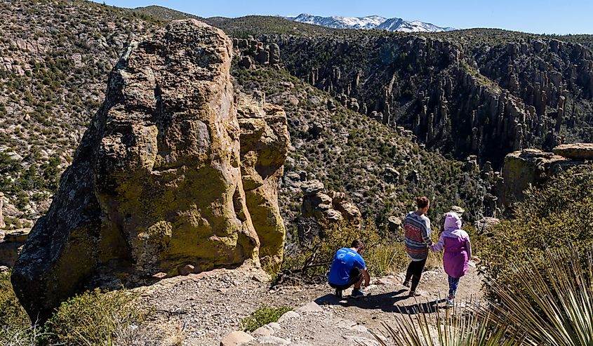 Hikers climb rock pinnacles which afford grand views of snow covered peaks and the valley below in Chiricahua National Monument in Southeastern Arizona.