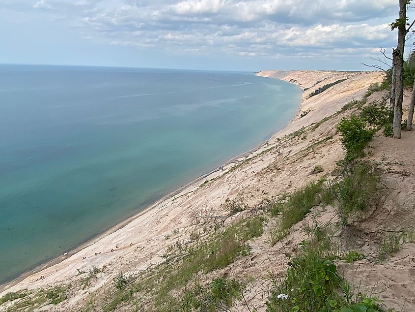A massive sand dune shoreline. A tiny line of climbers can be seen working their way up.