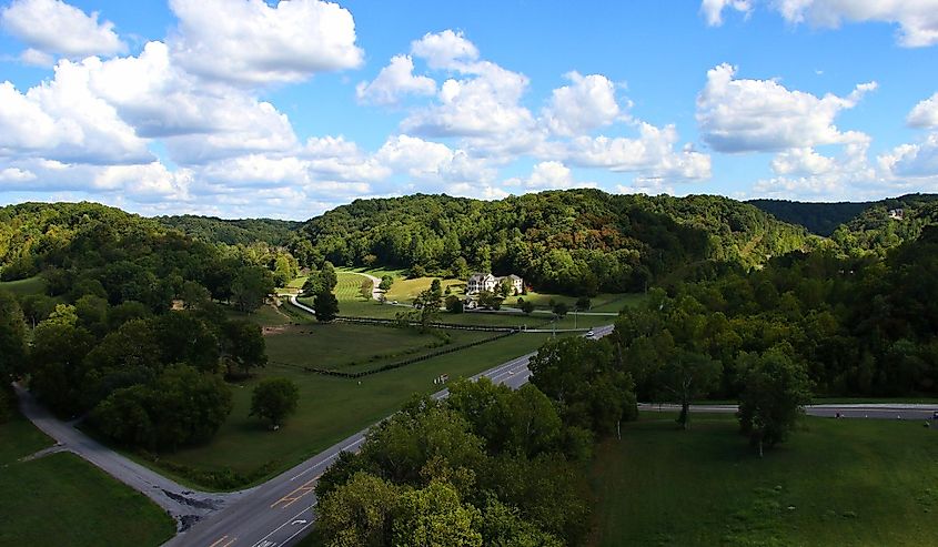 Over looking mansion and green fields with horses with hills behind Natchez Trace parkway