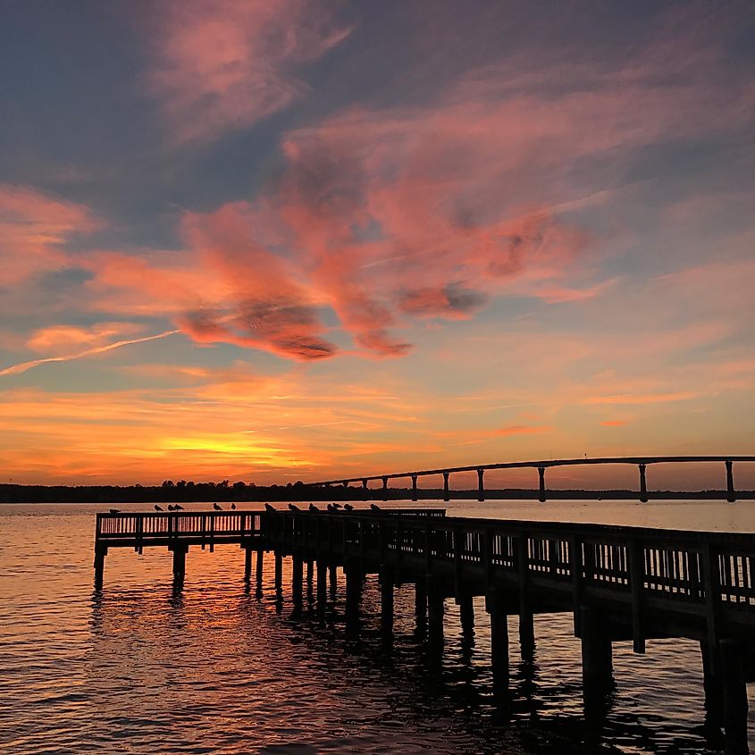 Solomons Sunset reflected on the Patuxent River with a pier and the Thomas Johnson bridge. 