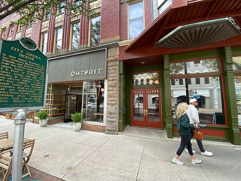 A couple strolls past the historic City Opera House and adjacent Outpost coffee shop in Traverse City, Michigan.
