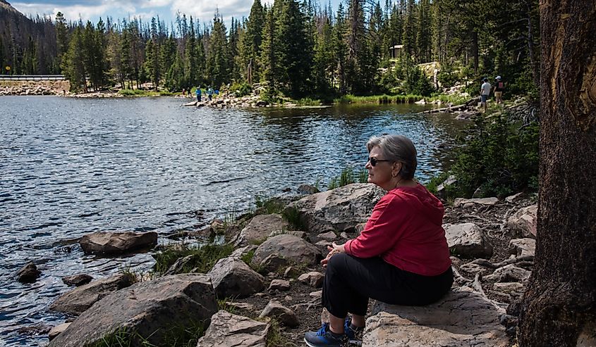 Woman in red shirt gazing over the tranquil waters of a high mountain lake, Kamas, Utah.