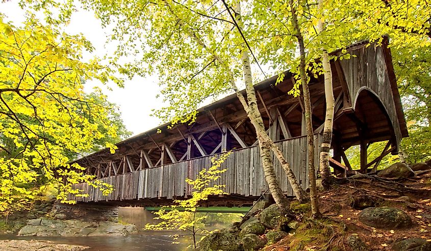 Covered bridge located in Newry, Maine with green trees and river flowing underneath