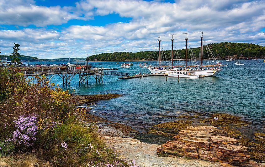Rocky coast and view of boats in the harbor at Bar Harbor, Maine. 