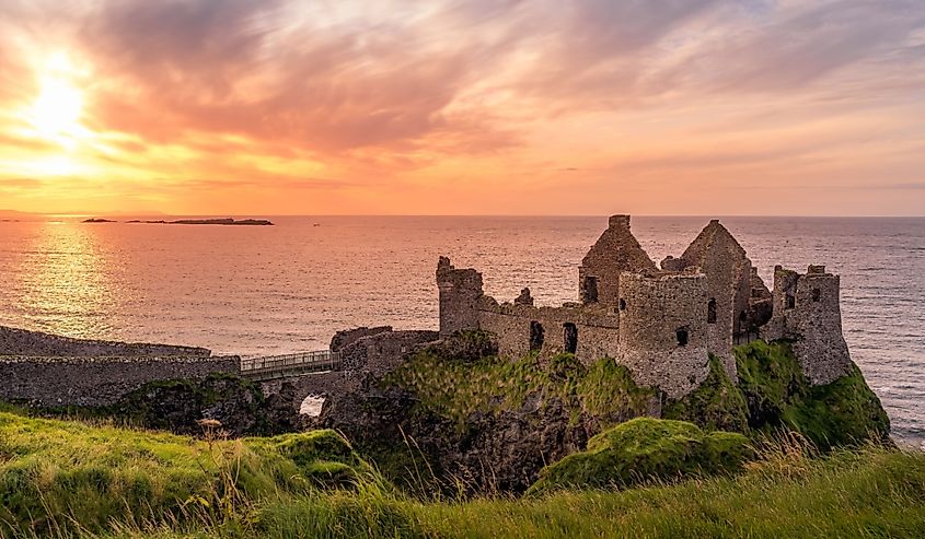 Ruined medieval Dunluce Castle on the cliff at amazing sunset, Wild Atlantic Way, Bushmills,