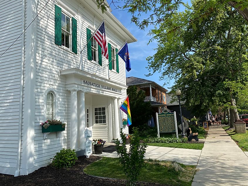 The white panelled facade of Saugatuck's Village Hall, flying the American, City, and Pride flags