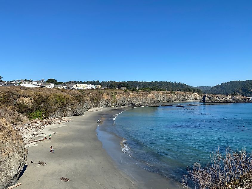 A low tide beach unfurls from steep coastal cliffs.