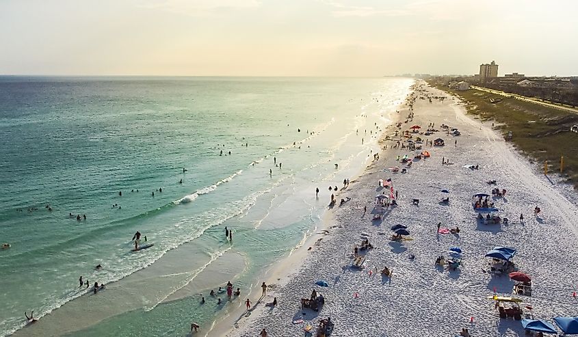 West of Miramar Beach in South Walton, Destin Florida with miles of sugar-white sandy beaches, turquoise water, gorgeous shade blue waves and crowed people relaxing, swimming, laid-back.