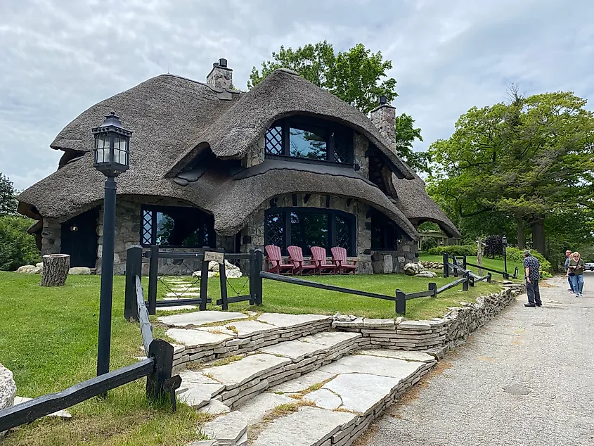 A few pedestrians checking out a massive, mushroom-shaped (and styled) house. 