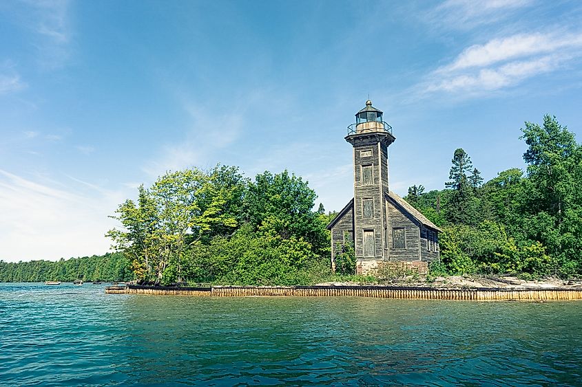 An old wooden lighthouse stands amongst the dense forests of Grand Island and before the blue waters of Lake Superior.