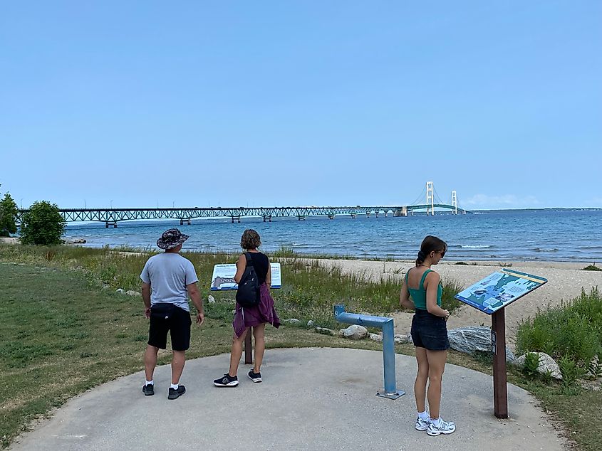 Tourists reading the historical signs beside Michigan's lengthy suspension bridge, Mackinac Bridge.