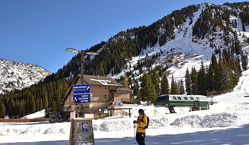 Горнолыжный курорт Альта с лыжником, одетым в желтое пальто, рядом с дочерним коттеджем Goldminers
