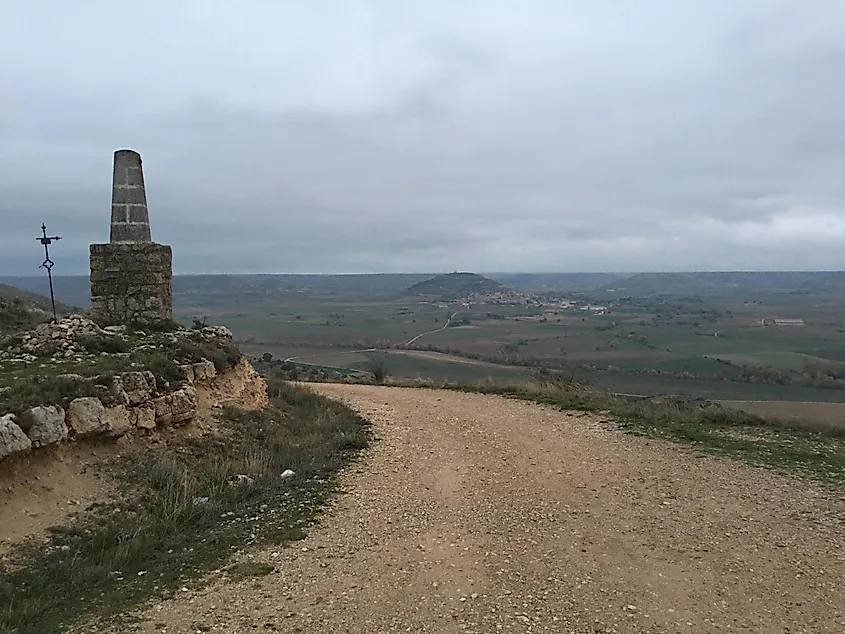 A gravel road prepares to descend a large hill and stretch onwards as far as the eye can see across the Spanish prairies. 