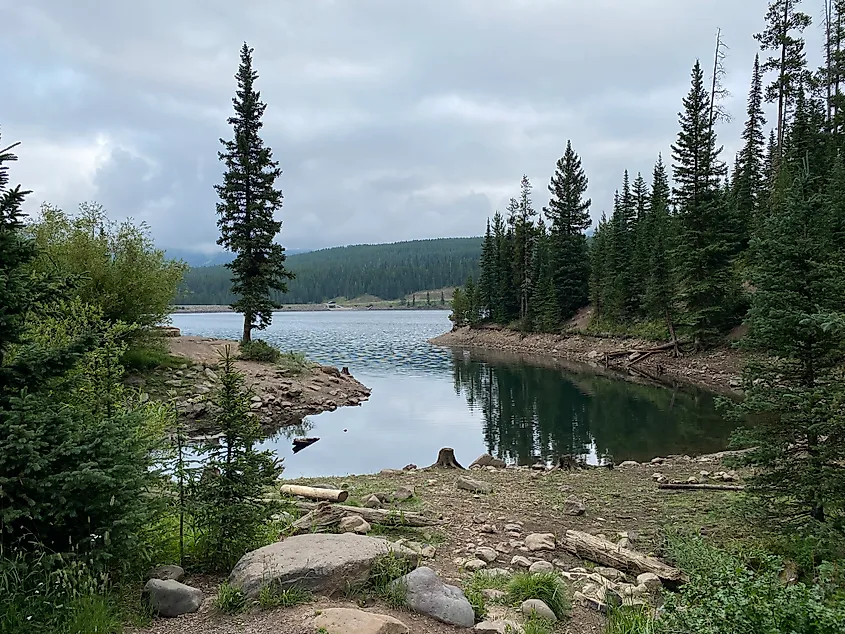 A small cove of a large mountain reservoir. Clouds overhead set a moody scene.