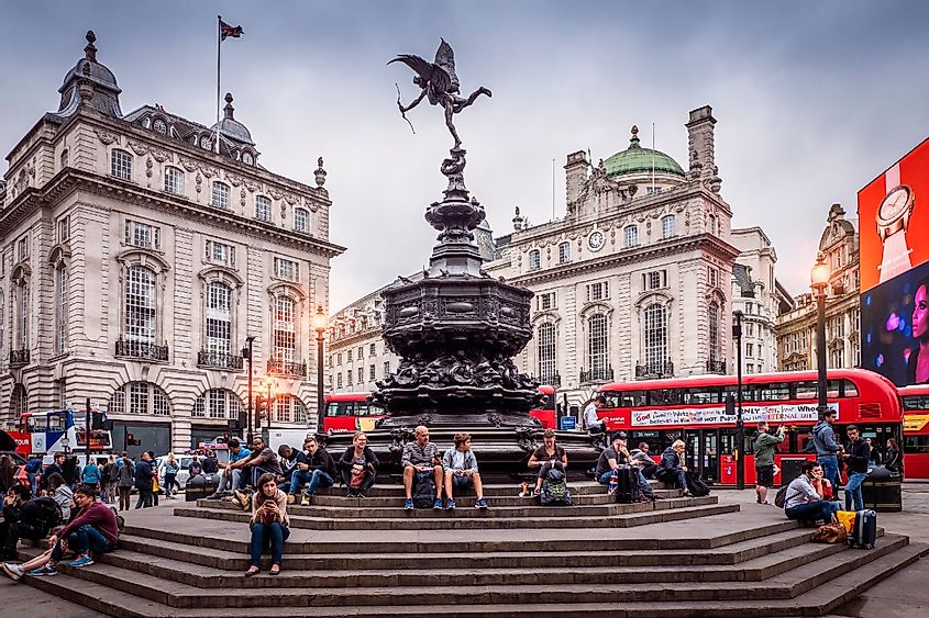 The historic architecture of London in the United Kingdom at sunset showcasing Piccadilly Circus with lots of locals and tourists passing by.