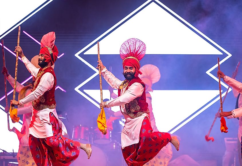 Bikaner, Rajasthan, India - January 14 2023: Group of punjabi artists from punjab performing bhangra dance in traditional colourful dress at bikaner camel festival.
