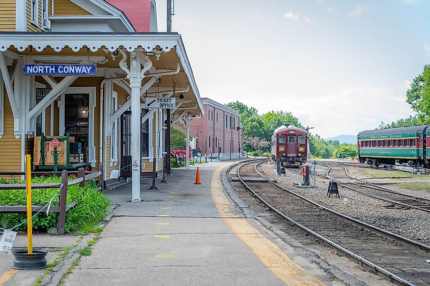 A scenic railcar parked beyond an empty platform at North Conway's historic rail depot.