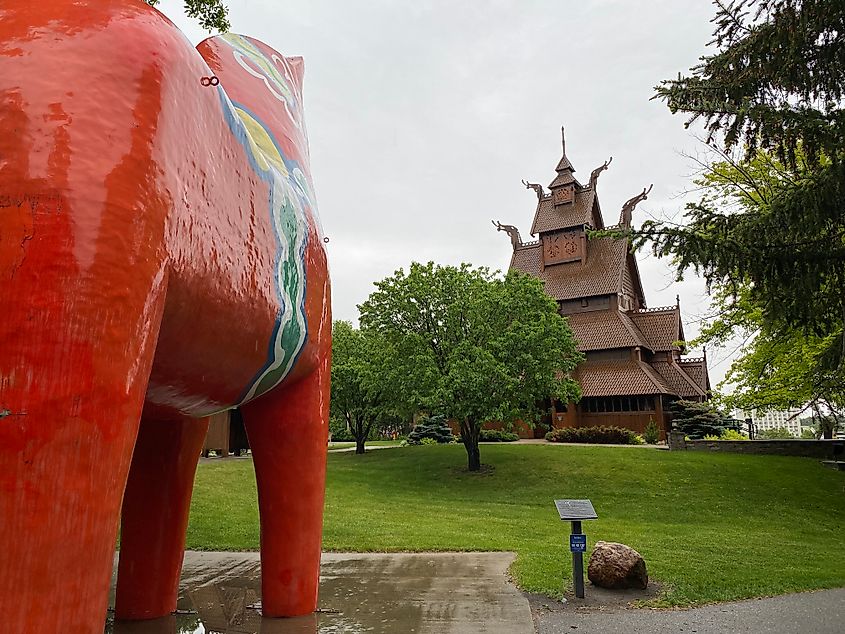 A giant red horse sculpture overlooking an even bigger wooden Norwegian church.