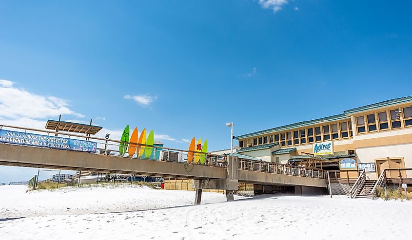 Okaloosa Island fishing pier in Florida in Panhandle, Gulf of Mexico during sunny day, colorful surfboards, restaurant bar