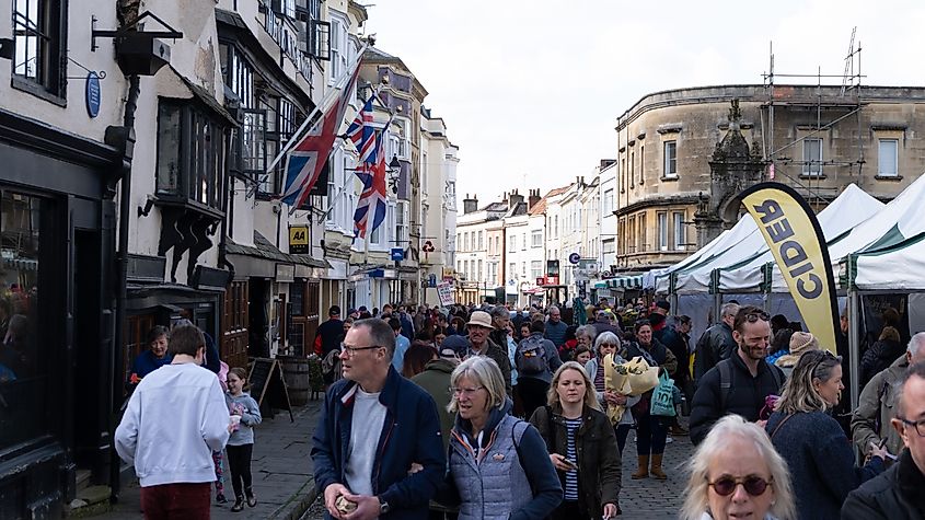 Busy crowds of people visiting and shopping at the popular fruit, vegetable, arts and crafts market in the city centre