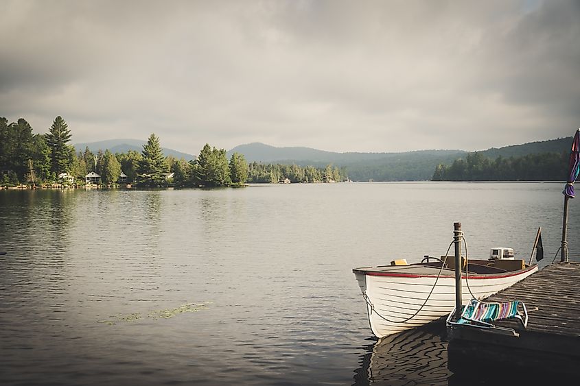 A boat sits on Blue Mountain Lake in a moody summer scene in Indian Lake, New York in the Adirondack Mountains.