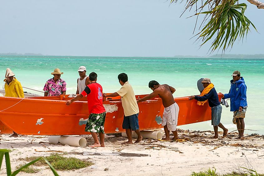 A group of men come in from a fishing trip to pull their boat onto the beach in Kiribati, via Kara Math / Shutterstock.com