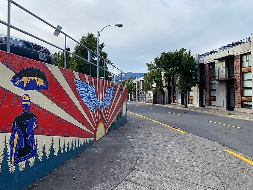 Edgy street art on the wall below a raised parking lot.