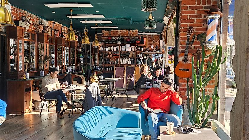 Helsinki, Finland - February 16, 2025: A stylish café-barbershop with vintage décor, exposed brick walls, warm lighting, and a cozy atmosphere where people relax, read, and enjoy drinks
