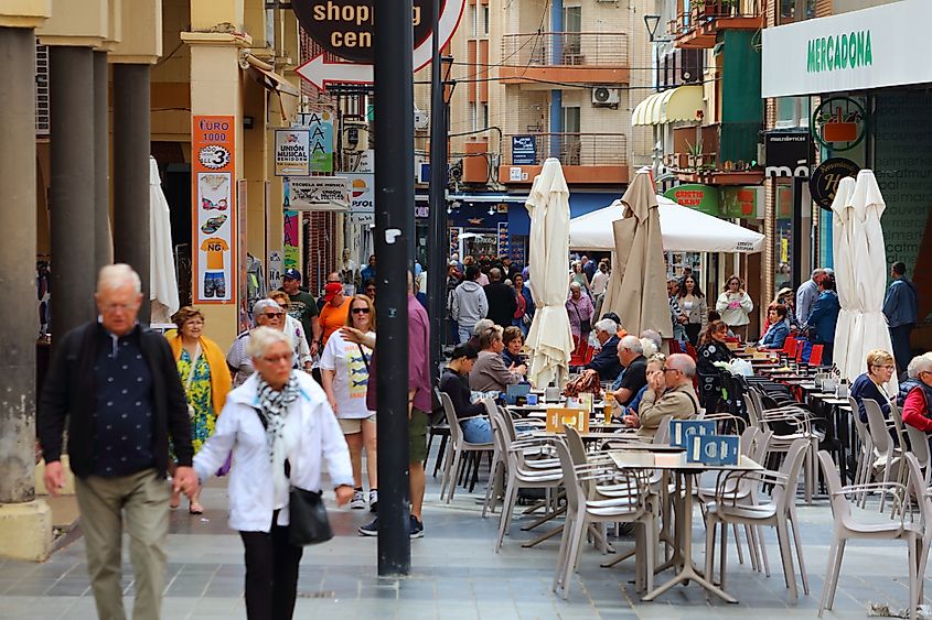 People walk along shopping street in downtown Benidorm resort town in Valencian Community, Spain.