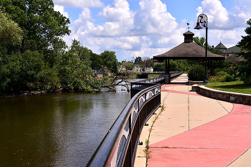 The walk way along the Fox River in Burlington Wisconsin on a beautiful mid summer afternoon with clouded blue skies and a pavilion along the walk. 