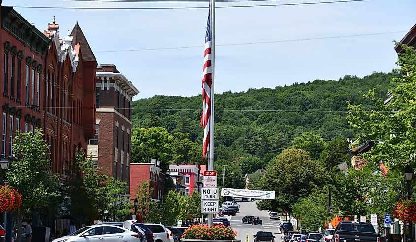 US Flag in the middle of the street and lush green trees frame the Main Street in Cooperstown, New York