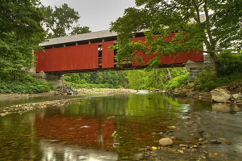 A tranquil North River reflects the Arthur A. Smith covered bridge near Colrain, Massachusetts seen from downstream