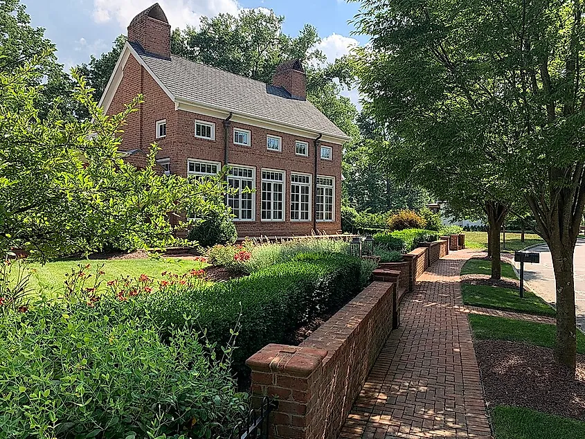 A red brick Georgian home and brick-paved sidewalk with vegetation in the Early Crossing neighborhood of New Albany, Ohio, 2019.