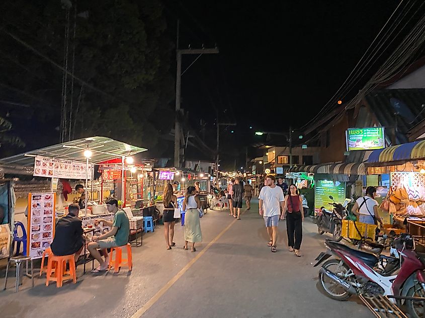 Western tourists walking along an Asian night market.