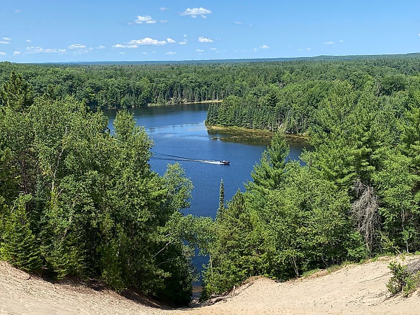 Watching a boat come up a forested river from high atop a sand dune.