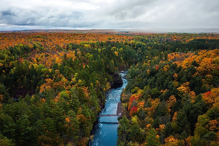 Beautiful aerial above the Bad River and a pedestrian foot bridge at Copper Falls in Mellen, Wisconsin.