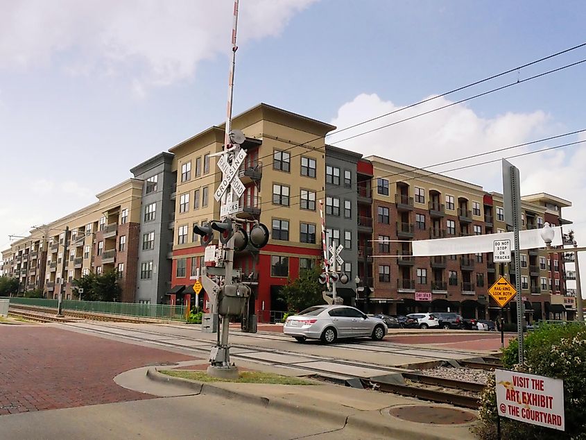 Railroad crossing sign with modern buildings in downtown Plano, Texas.