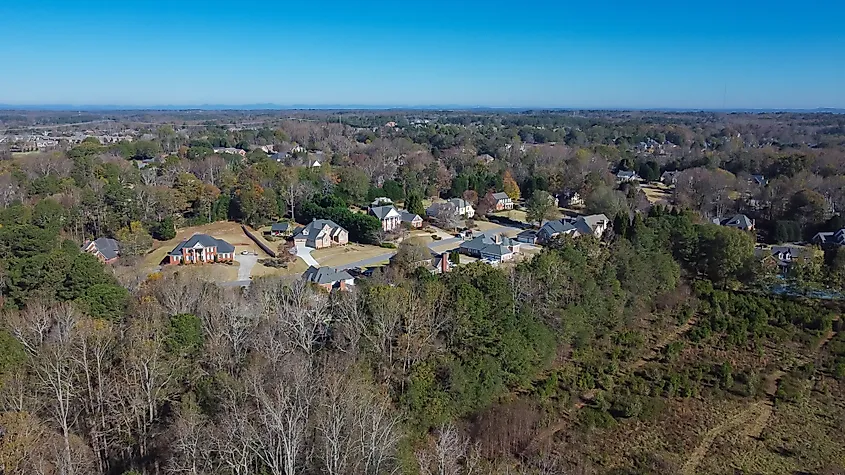 Chestnut Mountain and high voltage power lines over low density residential neighborhood in lush green forest area Flowery Branch, Georgia
