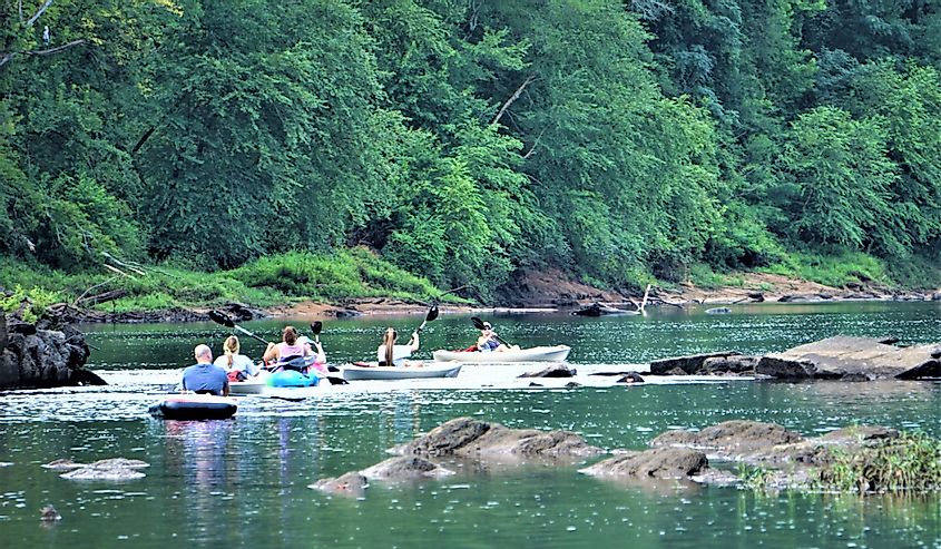 The tourists rowing rubber dinghy in the Oconee river on the background of green forest ,river and the rock.