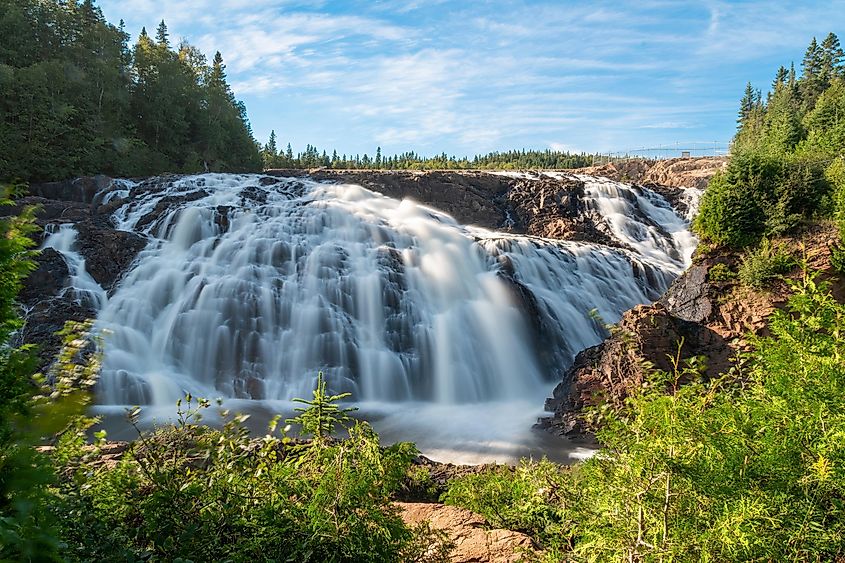 Wawa Falls in the small town of Wawa, Ontario, cascades down a rocky hill during an early evening sunset.