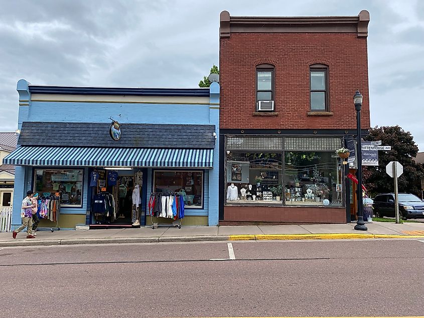 A man walks past the boutique shops of a small town's main street.